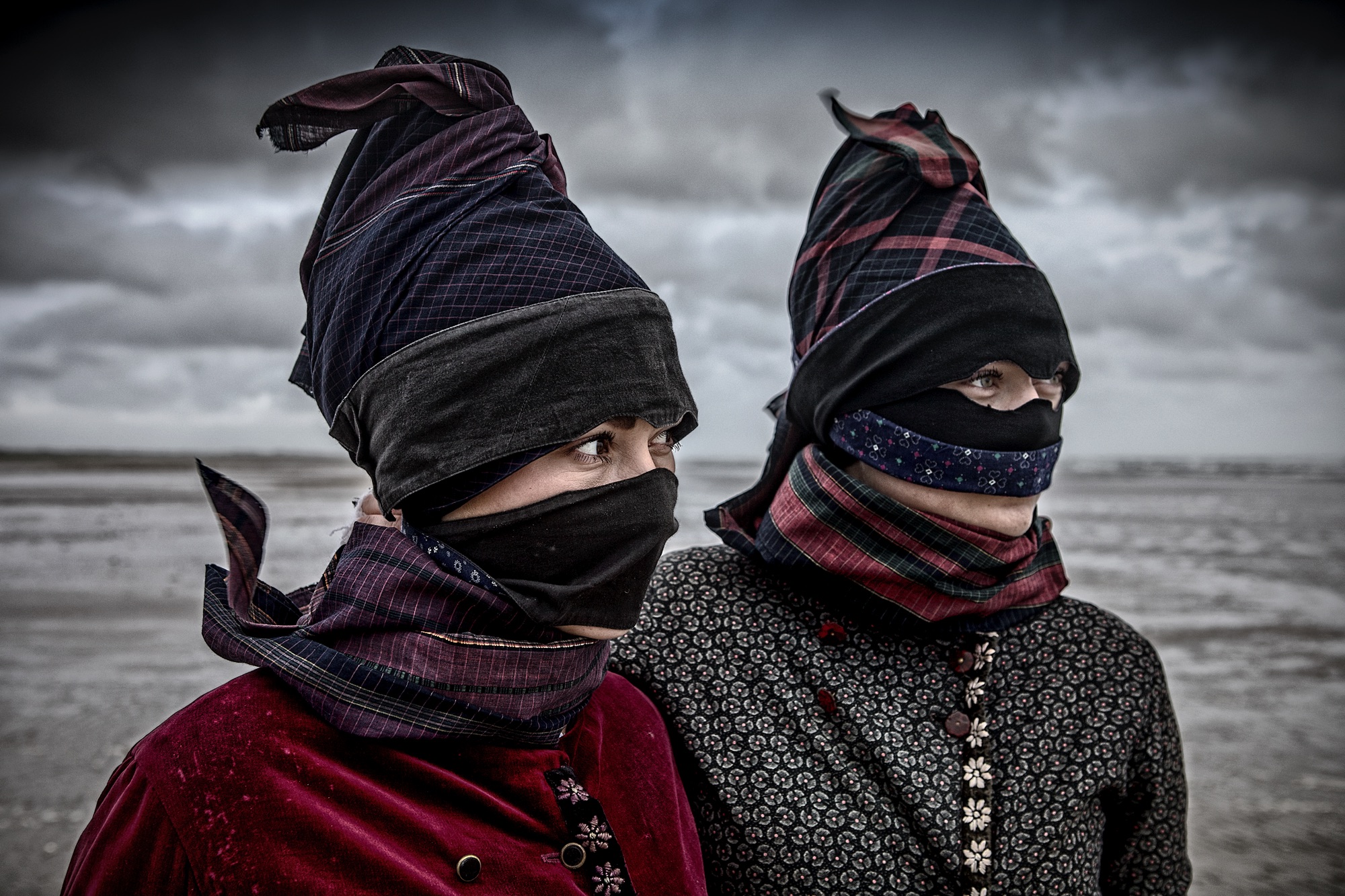 Foto af to kvinder i Fanødragt med strude (maske) – Ormegravere på Fanø – fotografi af Ole Joern billedet hænger på Fanø Bryghus